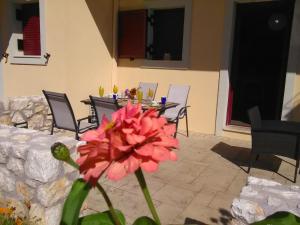 una flor rosa frente a una mesa con sillas en Mikros Gialos Apartments en Mikros Gialos