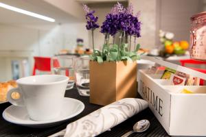 a table with a coffee cup and a vase with purple flowers at B&B In Centro Palermo in Palermo