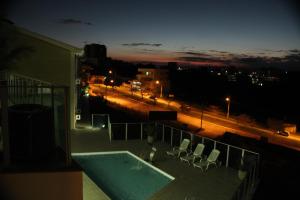 a balcony with chairs and a swimming pool at night at Serra Palace Hotel in Ouro Branco