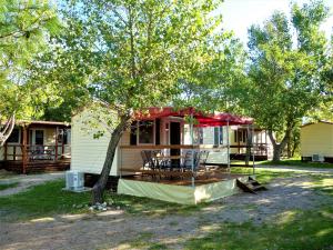 uma casa com uma mesa e cadeiras debaixo de uma árvore em Campsite Pisak - mobile homes by the sea em Seline