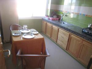 eine kleine Küche mit einer Spüle und einem Tisch mit Tellern darauf in der Unterkunft Villa Saraya in Mehdiya-Plage