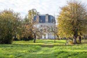 una casa vieja en un campo con árboles en Chambres d'Hotes Château de la Puisaye, en Verneuil d'Avre et d'Iton