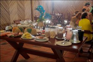 einen Tisch mit Tellern und Menschen, die um ihn herum sitzen in der Unterkunft Pousada Amor a Mar in Icapuí