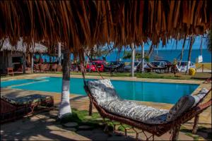 a pair of chairs under an umbrella next to a swimming pool at Pousada Amor a Mar Pé na Areia na Praia de Barreiras, Icapuí in Icapuí +82 photos