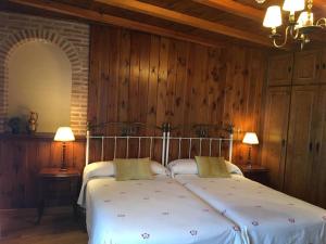 1 dormitorio con 1 cama blanca grande y paredes de madera en El Barondillo en Rascafría