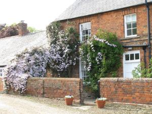 una casa de ladrillo con un árbol floreciente delante de ella en Newton Park Farm, en Turvey