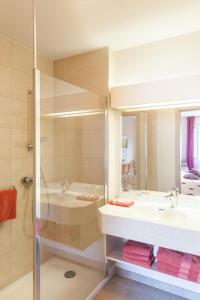a bathroom with a shower and a sink and a tub at Hotel Les Remparts in Kaysersberg