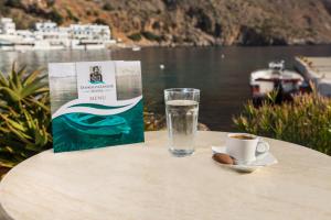 
a table with a glass of water and a plate of food at Daskalogiannis Hotel in Loutro
