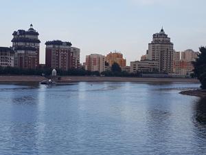 a river in a city with buildings in the background at Prestige in Astana