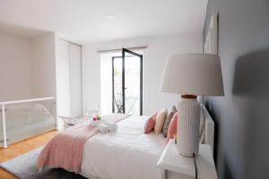 Dormitorio blanco con cama y lámpara en 2 Towers Apartment, en Ponta Delgada