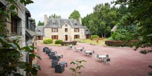 une cour avec des chaises et des tables ainsi qu'un bâtiment dans l'établissement Manoir De L'Acherie, à Sainte-Cécile