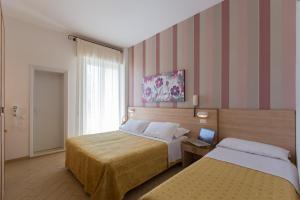 a hotel room with two beds and a laptop on a table at Hotel La Capinera in Bellaria-Igea Marina