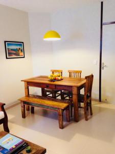 una mesa de madera con 2 sillas y una mesa con fruta. en Apartamento Cabo Frio 3Q, en Cabo Frío