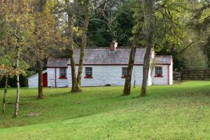 a white house with red windows in a field with trees at Railway Crossing Cottage in Murlas Bridge