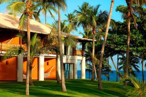 a house with palm trees in front of the ocean at Tivoli Ecoresort Praia do Forte in Praia do Forte