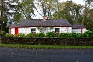 a small white house behind a stone wall at Railway Crossing Cottage in Murlas Bridge