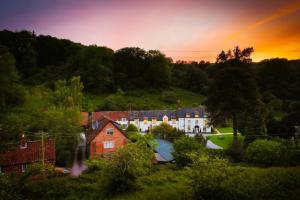 a house in a field with a rainbow in the sky at Combe House Hotel in Holford