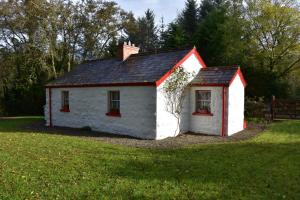 una piccola casa bianca con un tetto rosso in un cortile di Railway Crossing Cottage a Murlas Bridge