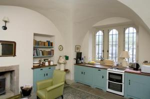 een keuken met blauwe kasten en een open haard bij Barbican in Glenarm