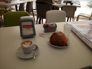 un tavolo con una tazza di caffè e un pasticcino e un cellulare di L'Oasi del Porto a Trapani