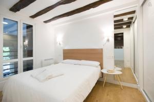 a white bedroom with a white bed and a window at LUXURY IN OLD TOWN NEAR BEACH by www,SanSebastianApartments,es in Donostia-San Sebastián