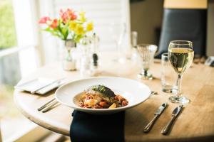 a plate of food on a table with glasses of wine at Combe House Hotel in Holford