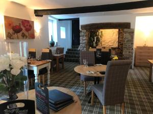 a restaurant with tables and chairs and a fireplace at Combe House Hotel in Holford