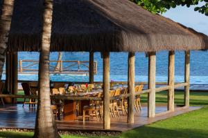a restaurant with a table with chairs and a straw roof at Tivoli Ecoresort Praia do Forte in Praia do Forte