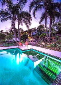 a swimming pool with palm trees and a house at Pousada The Rosebud in Praia do Rosa