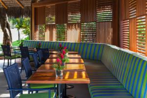 a restaurant with wooden tables and chairs with flowers on it at Tivoli Ecoresort Praia do Forte in Praia do Forte