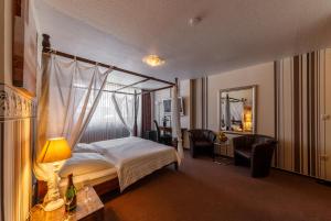 a hotel room with a bed and chairs and a mirror at City Hotel Stolberg in Stolberg