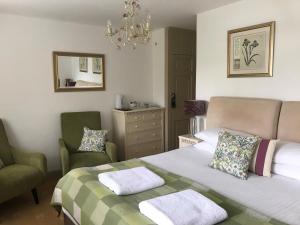 a hotel room with a bed, chair, table and lamp at Combe House Hotel in Holford