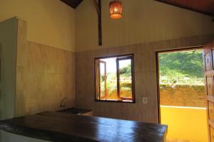 a kitchen with a counter and a window at Pousada Recanto do Ypê in Aiuruoca