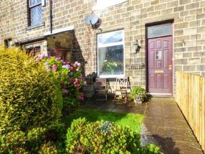 a house with a red door and a yard with flowers at Fell Cottage in Keighley