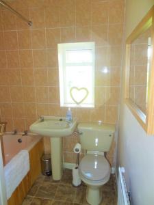 a bathroom with a toilet and a sink and a window at Fell Cottage in Keighley