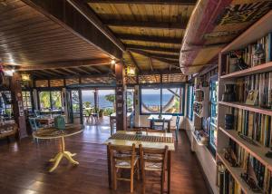 a room with a table and chairs and books at Pousada The Rosebud in Praia do Rosa