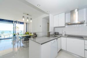 uma cozinha branca com armários brancos e uma mesa em Bennecke Primavera em Punta Prima