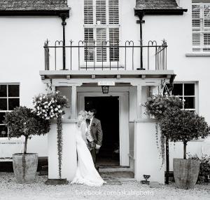 a bride and groom standing in front of a white house at Combe House Hotel in Holford
