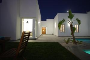 eine Villa mit einem Pool in der Nacht mit einem Stuhl in der Unterkunft Chalet Deluxe Wifi Gratis in Conil de la Frontera
