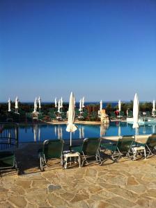 een groep stoelen en parasols naast een zwembad bij Ariadne Apartments in Tsilivi