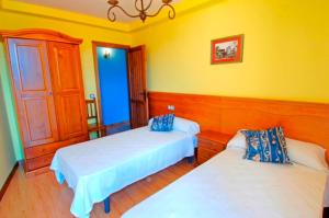 Duas camas num quarto com paredes amarelas em Apartamentos Sierra de Francia em Monsagro
