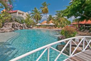 a beach scene with a pool and a balcony at Radisson Grenada Beach Resort in Grand Anse