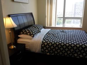 een slaapkamer met een bed met een lamp en een raam bij 2 BEDROOM 2 Bathroom Best Value Prime Location in Missisauga in Mississauga