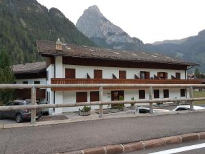 a building with cars parked in front of a mountain at Casa Penia 2 in Canazei