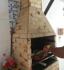 una persona está poniendo carne en un horno de ladrillo en Linda casa na Praia do Flamengo en Salvador