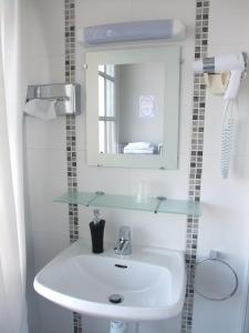 a white sink sitting under a mirror in a bathroom at Hôtel des Biches in Nuaillé