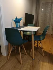 a table with two green chairs and a white table at Apartamenty Jesionowa in Wrocław