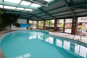 a large swimming pool with awning and blue water at Alton Lodge Motel in Whakatane