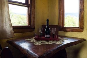 a bottle of wine sitting on a table with two glasses at Cabañas Quisama in Nono +42 photos