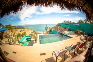 a pool with chairs and the ocean in the background at Palapas Ventana in La Ventana